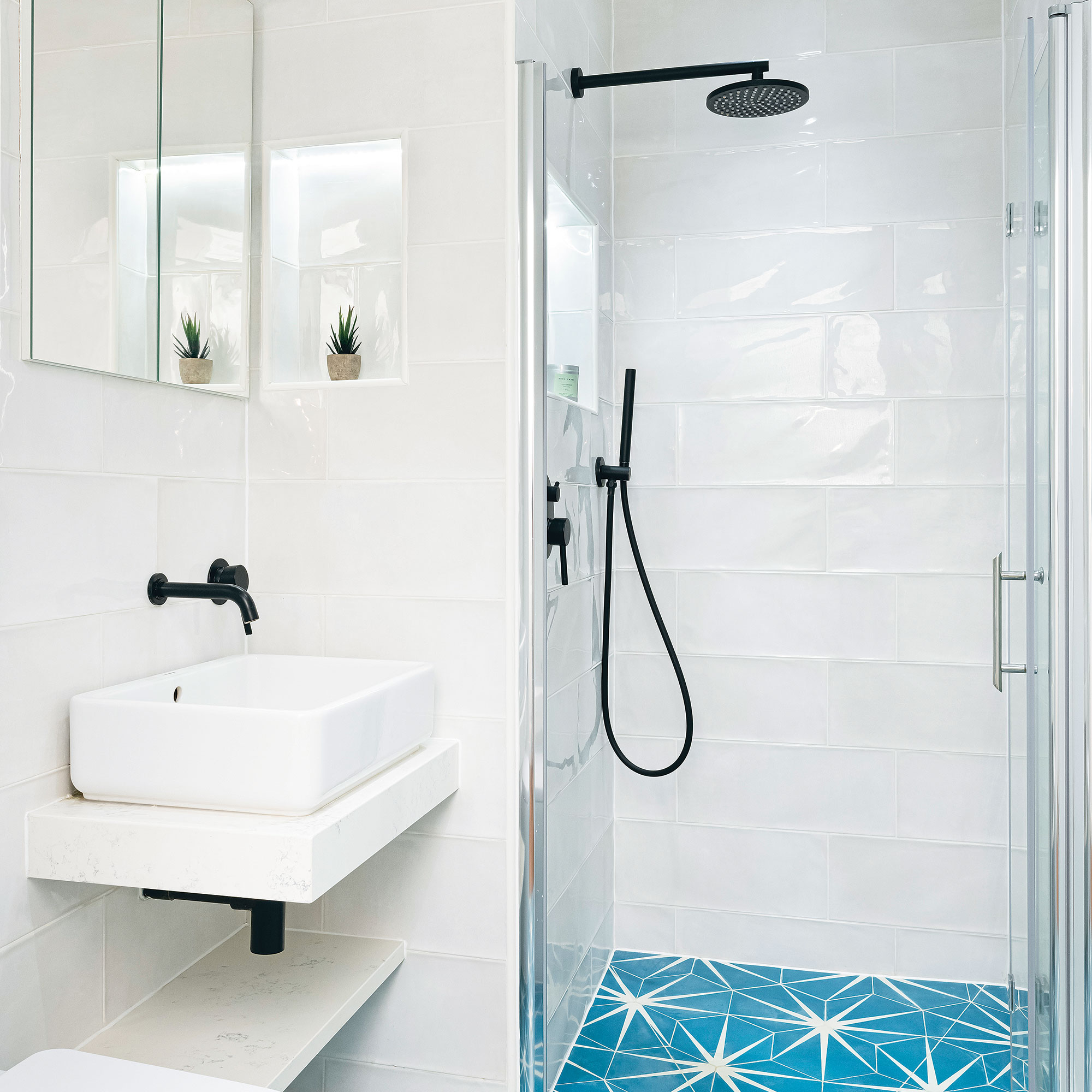 White bathroom with bright blue patterned tile shower floor