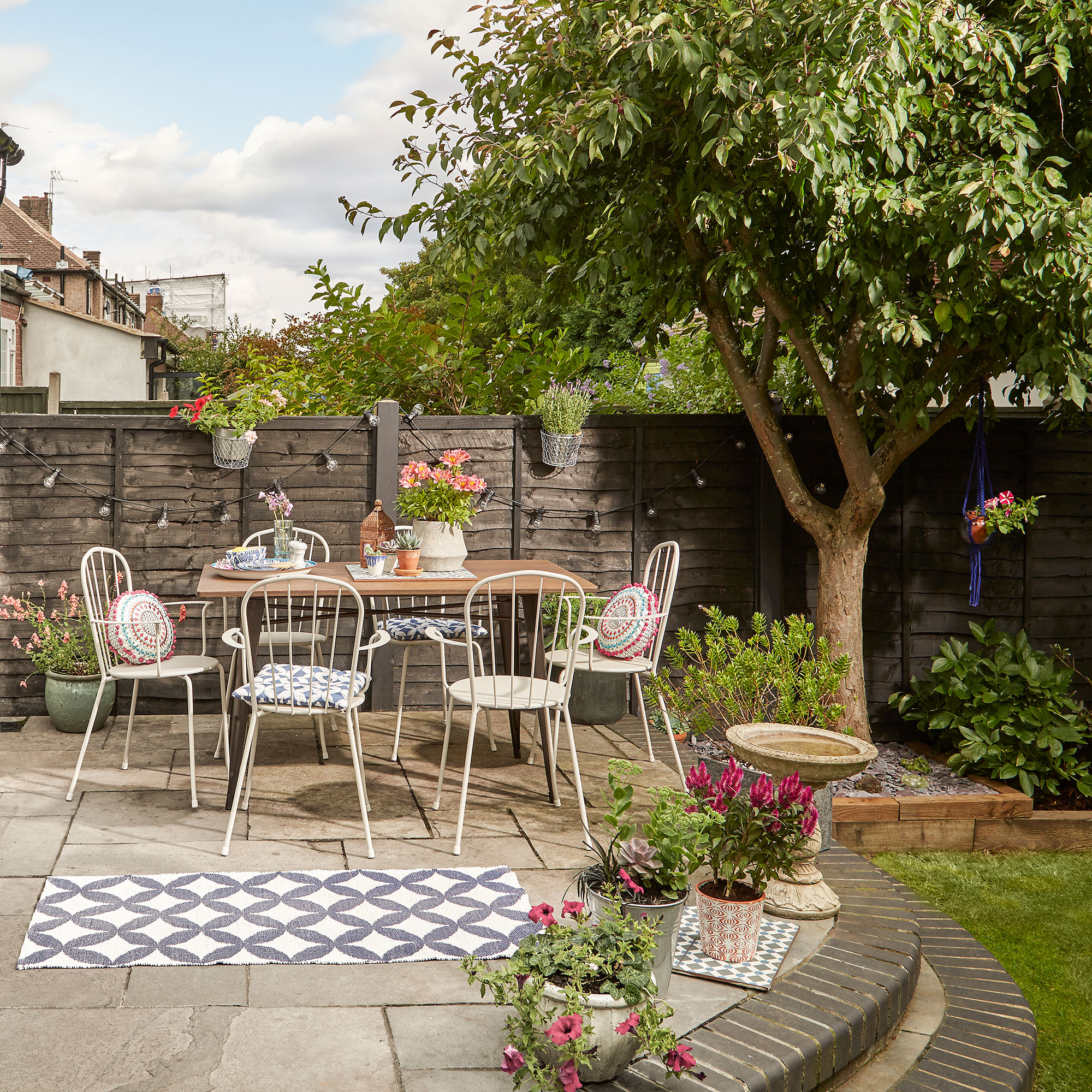 Garden makeover, patio with bamboo and metal table and white metal chairs.