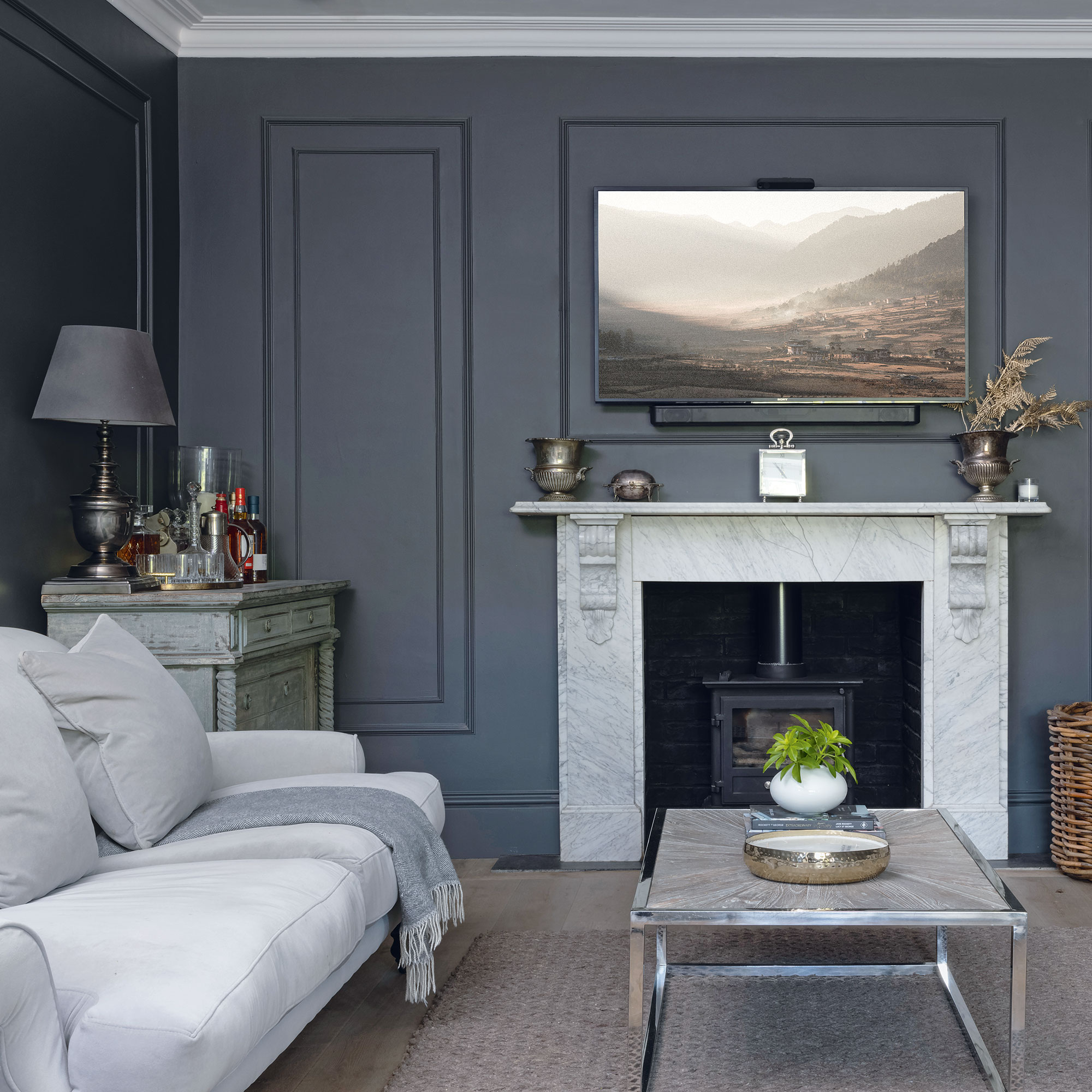 Dark grey painted living room with pale grey sofa and large fireplace